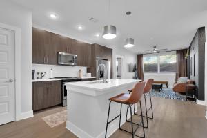 Luxury 2-Bedroom Apartment Near The Battery Atlanta with Pool, Sky Lounge & Free Parking في أتلانتا: مطبخ مع كونتر ابيض وبعض الكراسي