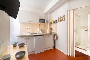 a small kitchen with white cabinets and a sink at Studio cosy et lumineux Centre de Beaucaire - cocon 3 in Beaucaire
