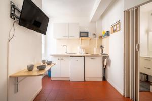 a kitchen with white cabinets and a tv on the wall at Studio cosy et lumineux Centre de Beaucaire - cocon 3 in Beaucaire +3 photos