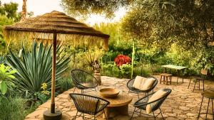 Un patio con sillas, una mesa y una sombrilla. en Riad chama, en Taroudant
