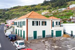 a white house with green doors in a parking lot at Casa da Georgina by GALMI in Arco da Calheta