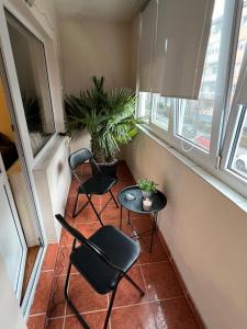 two chairs and a table in a small room with windows at Apartament doua camere in Baia Mare