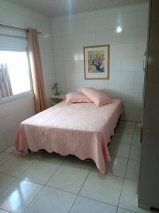 een slaapkamer met een bed met roze lakens en een raam bij Casa de praia ideal para relaxar in Torres