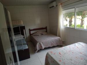 een slaapkamer met twee bedden en een raam bij Casa de praia ideal para relaxar in Torres