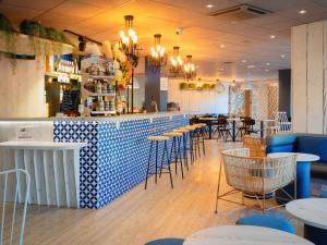 a restaurant with a bar with blue and white tiles at ibis Manosque Cadarache in Manosque