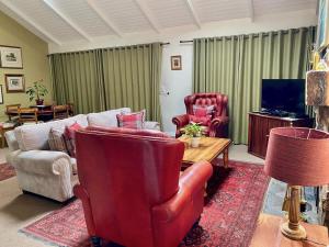 a living room with a couch and chairs and a tv at Willow Weir River Cottage in Dullstroom