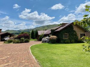 a house with a brick driveway and green grass at Willow Weir River Cottage in Dullstroom
