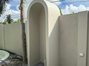 クタにあるZENARA lombokのヤシの木の隣の壁にあるアーチ道