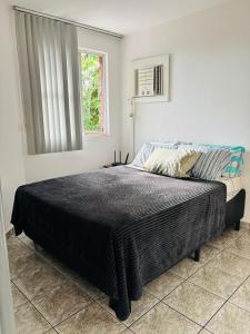 a bedroom with a large bed in a room with a window at Enseada Azul Home in Guarapari