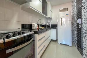 Una cocina blanca con estufa y refrigerador. en Apartamento Centro, en Guarapari