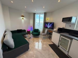 a living room with a green couch and a television at Appartement 2 pièces - 550mètres du metro 13 in Saint-Denis