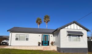 a white house with palm trees on top of it at Queensly Cottage in Portland