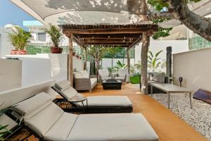een buitenterras met witte meubels en een pergola bij Villa Lol Tun Breakfast and Beach Club Included in Isla Mujeres