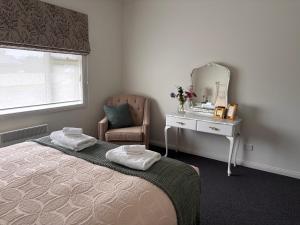 a bedroom with a bed and a mirror and a chair at Queensly Cottage in Portland