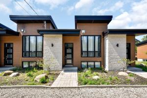 Agora Duo Portneuf - 2 Family Units - 2 Private Spas في Pont-Rouge: منزل من الطوب ونوافذ سوداء