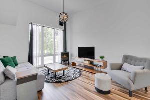 Agora Duo Portneuf - 2 Family Units - 2 Private Spas في Pont-Rouge: غرفة معيشة مع أريكة وتلفزيون