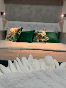 a bed with green pillows and a white blanket at Pousada Residencial A Dantas in Búzios +86 photos