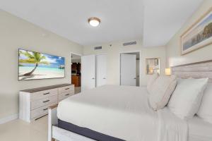 Cette chambre comprend un lit blanc et une télévision murale. dans l'établissement Luxury Waterfront W Hotel Condo Brickell Skyline Views, à Miami