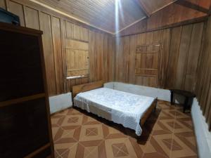 a small bedroom with a bed in a room with wooden walls at Sitio alto valinhos in Itamonte