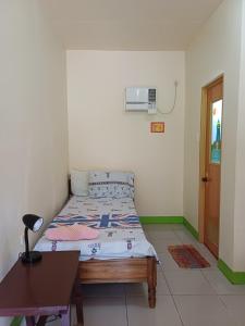 a small bedroom with a bed and a table at Calitang Pearl Cottage in Nacpan
