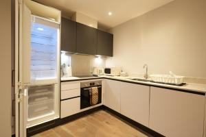 a kitchen with white cabinets and a refrigerator at Modern & Cozy Flat in the Heart of Chelmsford - F7 in Chelmsford