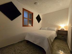 um quarto com uma cama branca e uma janela em Rincon Urbano Tunja Alojamiento em Tunja