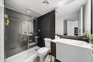 a bathroom with a toilet and a shower and a sink at Spacious Downtown Condo - Walk to CN Tower & More in Toronto