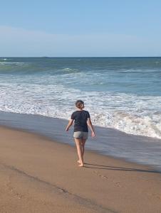 a woman walking on the beach near the ocean at Casa Amarela in São Francisco do Sul +3 photos