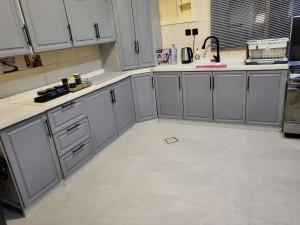 a kitchen with white cabinets and a tile floor at المسكن الزاهي الامير فواز in Jeddah +11 photos