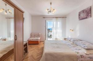a bedroom with a bed and a chair and a window at Apartments and rooms by the sea Tucepi, Makarska - 24679 in Tučepi