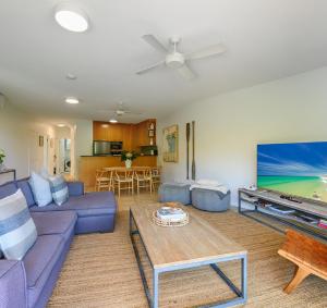 5 "Sempre" 28-34 Duke St Sunshine Beach في صن شاين بيتش: غرفة معيشة مع أريكة زرقاء وتلفزيون