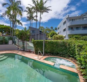 5 "Sempre" 28-34 Duke St Sunshine Beach في صن شاين بيتش: حمام سباحة أمام مبنى به أشجار نخيل