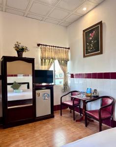 a room with a kitchen and a table and a refrigerator at Nam Đô Hotel Cần Thơ Downtown in Can Tho