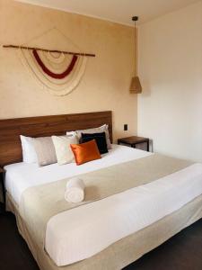 1 dormitorio con 1 cama grande con almohadas de color naranja y blanco en Aruma Suites, en Playa del Carmen