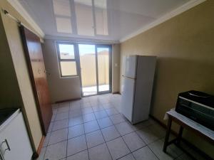 an empty kitchen with a refrigerator and a door at Bird Retreat in Zeekoevlei