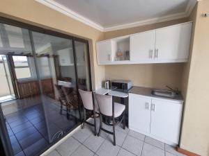 a kitchen with white cabinets and a table and chairs at Bird Retreat in Zeekoevlei