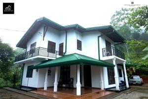 a white house with a green awning at Tea Escape Holiday Villa and Cabanas in Gampola