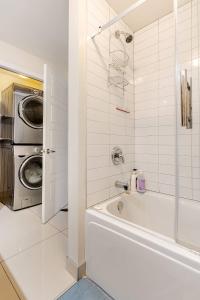 a bathroom with a tub and a washing machine at Voltaire 2 Appartement 4,5 , 2ch Laval, Canada meublé in Laval +13 photos