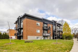 a large brick building with a grass yard in front of it at Voltaire 2 Appartement 4,5 , 2ch Laval, Canada meublé in Laval
