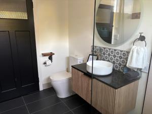 a bathroom with a sink and a toilet and a mirror at Queensly Cottage in Portland +31 photos