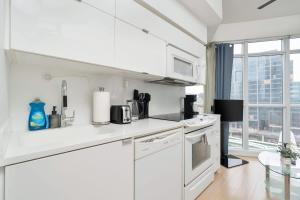 a kitchen with white appliances and a large window at Sunny Downtown TO Studio - Sleeps 3 with 55 TV in Toronto