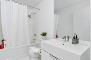 a white bathroom with a tub and a toilet and a sink at Sunny Downtown TO Studio - Sleeps 3 with 55 TV in Toronto