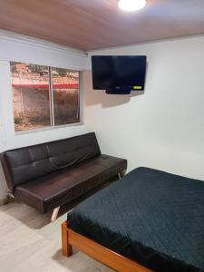 a bedroom with a couch and a flat screen tv at Casa Alto de la Virgen DeMaiz in Choachí +5 photos