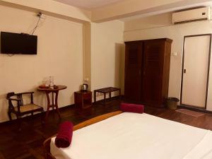 a bedroom with a bed and a table and a tv at Omega Regency Colombo in Colombo