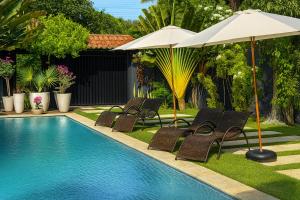 a swimming pool with chairs and an umbrella at Harmonia Flats in Pipa