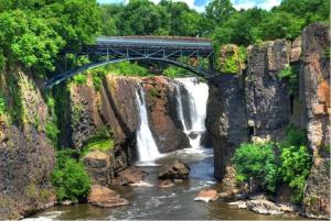 a train traveling over a bridge over a waterfall at Modern Luxury Executive Room with NYC Fast Access in Paterson