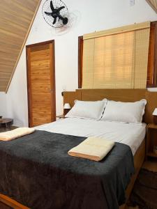 a bedroom with a large bed with two towels on it at Chalé Alpes da Nascente in Salesópolis