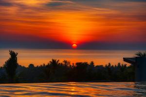 a sunset over the ocean with a swimming pool at Villa Sabanya Sea View in Ban Nua