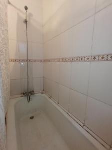 a bath tub in a room with white tiles at Monofacetas Plaza de Armas in La Serena