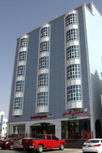 a red truck parked in front of a building at Dar Al Khaleej Hotel Apartments in Al Buraymī